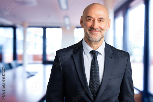 Portrait of senior businessman smiling and standing at the office