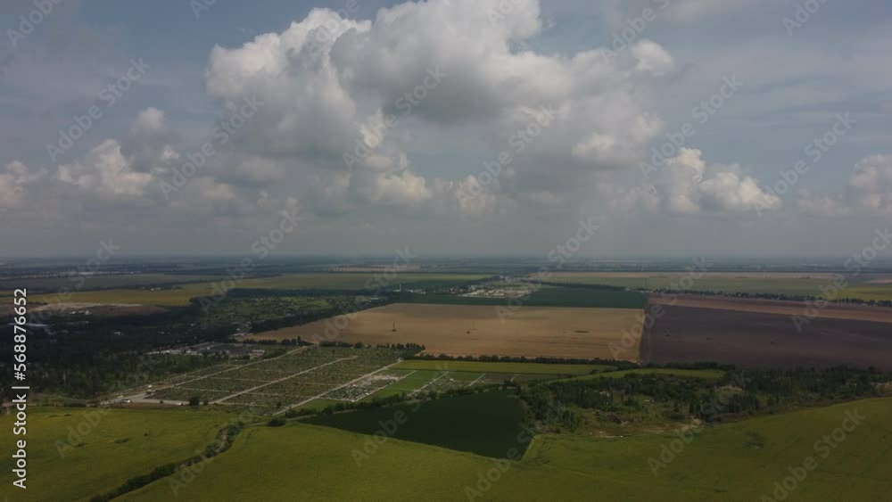 Fast moving of white clouds in sky above agrarian field of blooming sunflowers and different green agroindustrial fields, brown plowed field, field of ripe wheat on summer sunny day. Aerial drone view Fast moving of white clouds in sky above agrarian field of blooming sunflowers and different green agroindustrial fields, brown plowed field, field of ripe wheat on summer sunny day. Aerial drone view