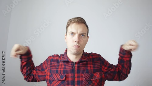 The man presses his hands on the edges of the frame and expands the frame. A man in a red shirt against a white wall. View from the laptop webcam. High quality FullHD footage