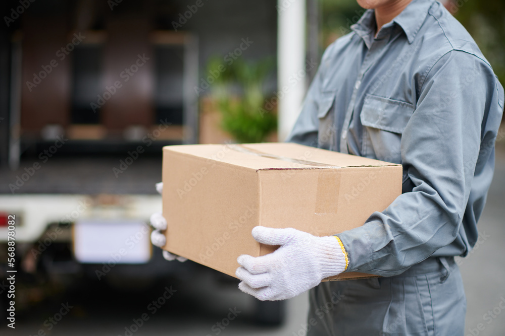 Mover with cardboard box standing in front of truck with opened Mover with cardboard box standing in front of truck with opened