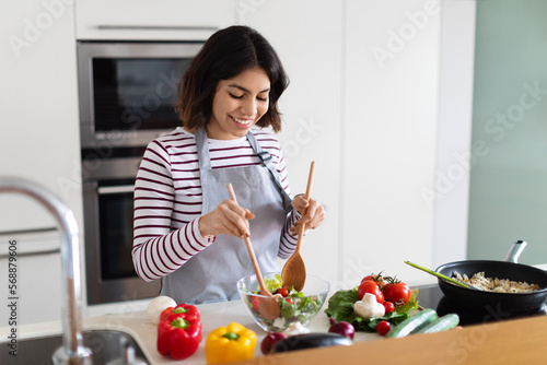 Cheerful young woman vegan making vegetable salad