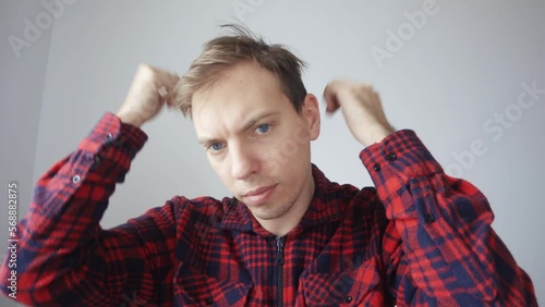 The young man turns on the webcam, notices that he has a bad hairstyle, combs his hair, turns on video communication, greets colleagues. View from the laptop webcam.