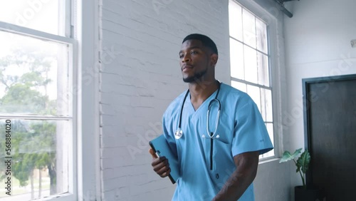 Black Stock Footage portraits of millennial Black man nurse working in a blue medical scrubs in the hospital corridor hallway with natural light