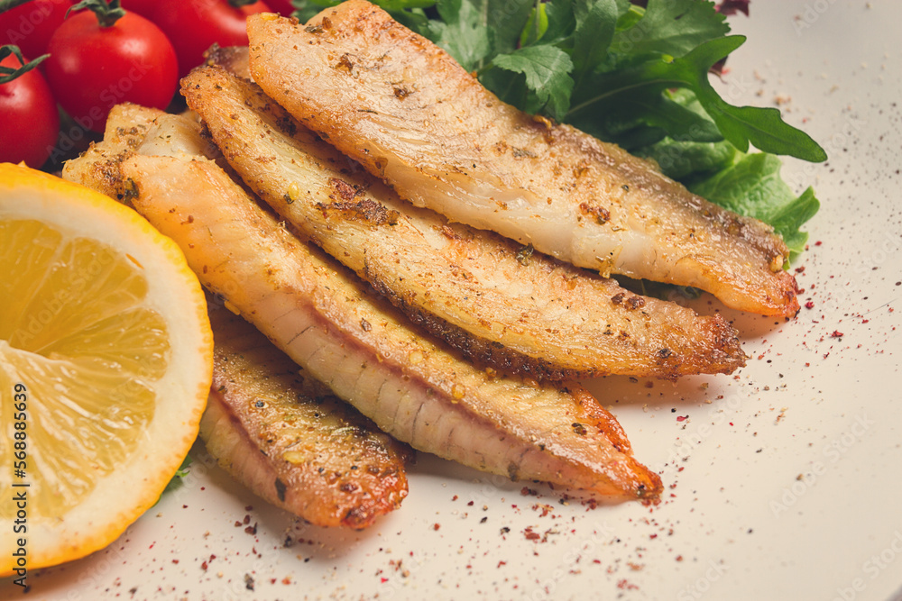 Fried Tilapia fish fillet, in spices, with cherry and salad, on a white plate, homemade, no people, Fried Tilapia fish fillet, in spices, with cherry and salad, on a white plate, homemade, no people,