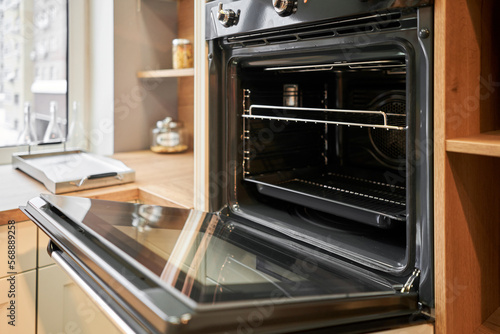 Electric oven with air ventilation. Side view of modern technology appliance against kitchen furniture.