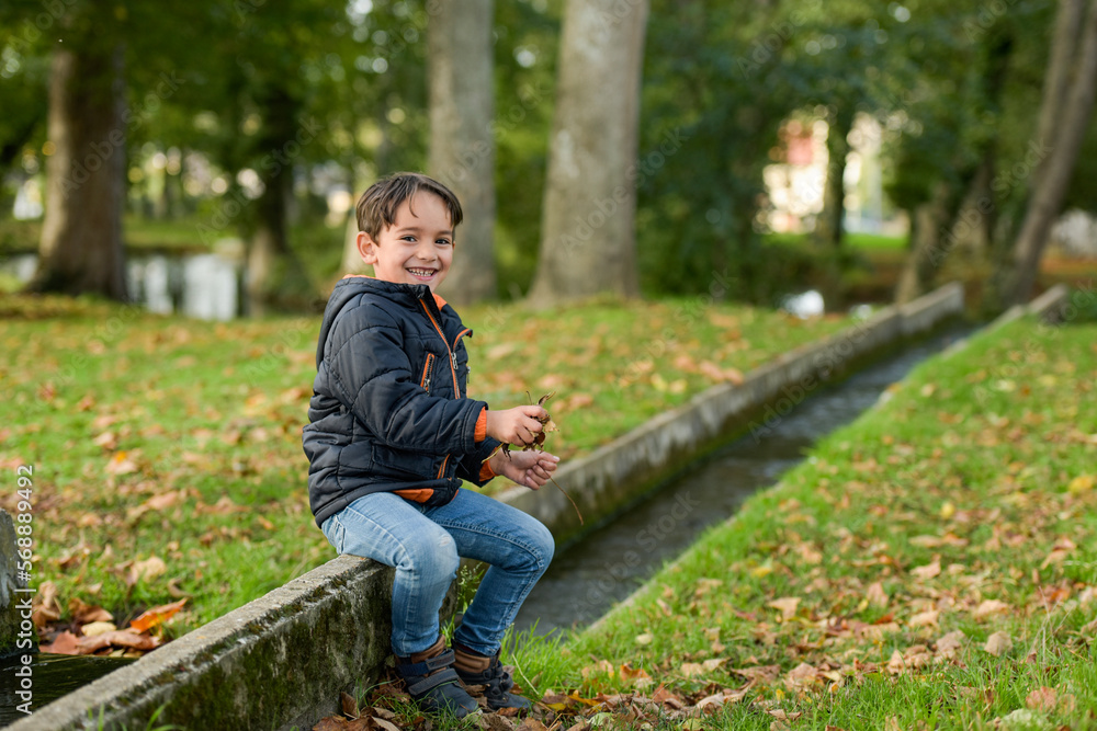 young caucasian boy playing in urban park in autumn