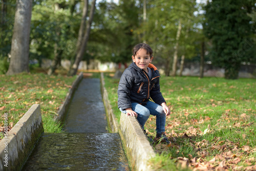 young caucasian boy playing in urban park in autumn