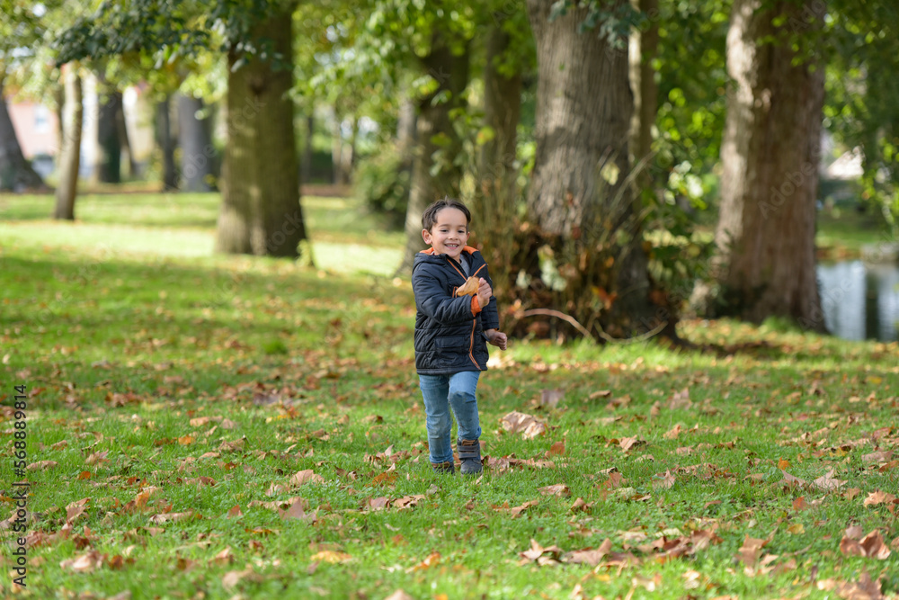 young caucasian boy playing in urban park in autumn young caucasian boy playing in urban park in autumn