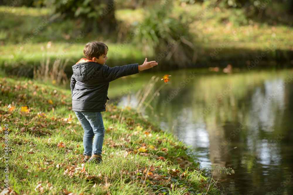 young caucasian boy playing in urban park in autumn young caucasian boy playing in urban park in autumn