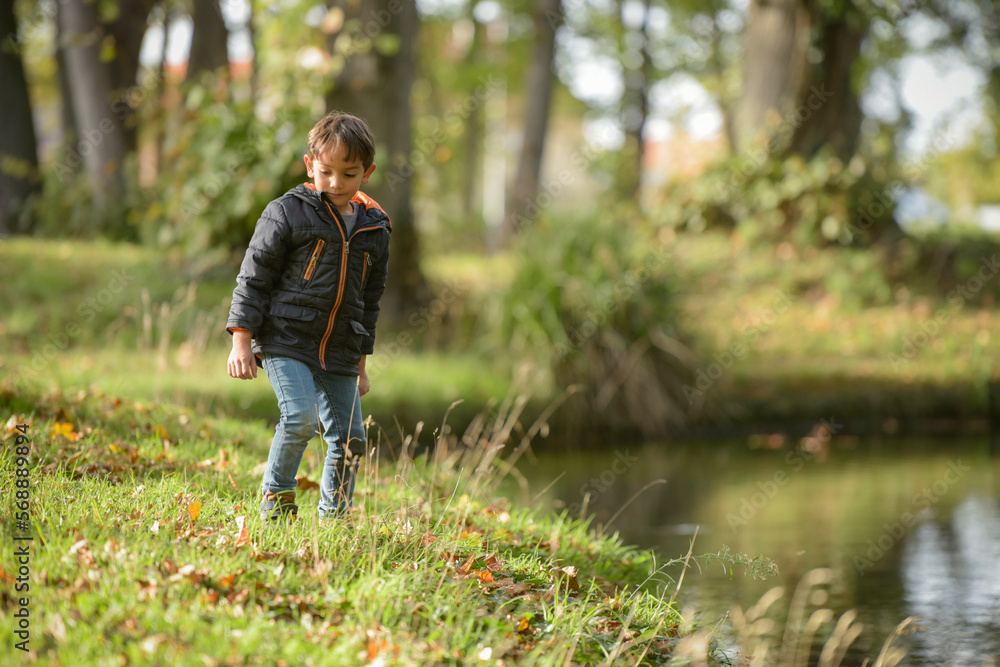 young caucasian boy playing in urban park in autumn young caucasian boy playing in urban park in autumn