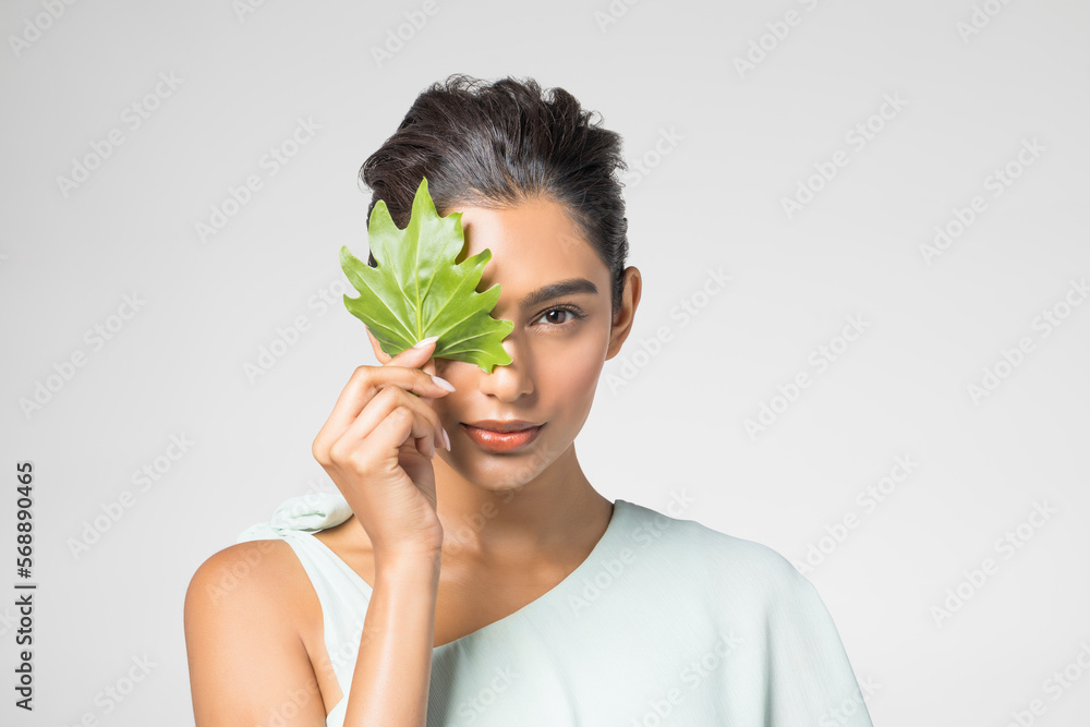 Studio portrait of beautiful woman with leaf on her face Studio portrait of beautiful woman with leaf on her face