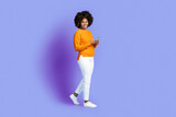 Pretty black woman using cell phone and smiling on purple