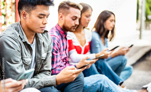 Bored people using smartphone sitting at university college campus - Young friends watching viral video on mobile smart phone - Technology life concept with always connected student - Bright filter