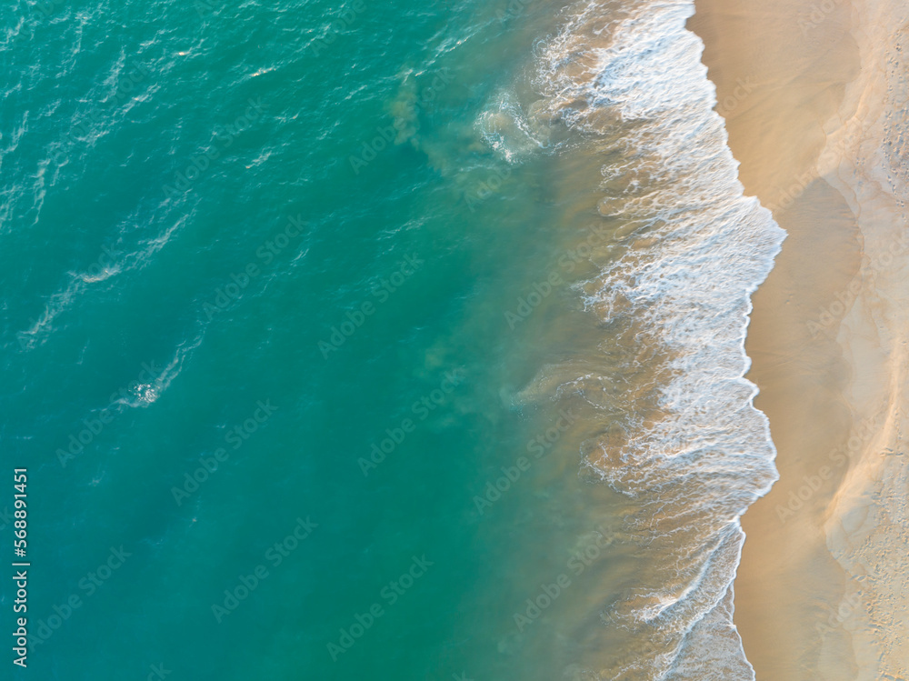 Beach top view of soft blue ocean wave on clean sandy beach and relaxing aerial scene, summer vacation holiday template banner. Waves surf with blue ocean lagoon	