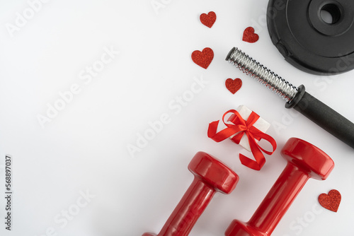 Gym dumbbells, engagement ring box and decorative red hearts as a love gift for Valentine's Day, Women's day, anniversary or wedding. Healthy fitness workout flat lay composition with copy space.