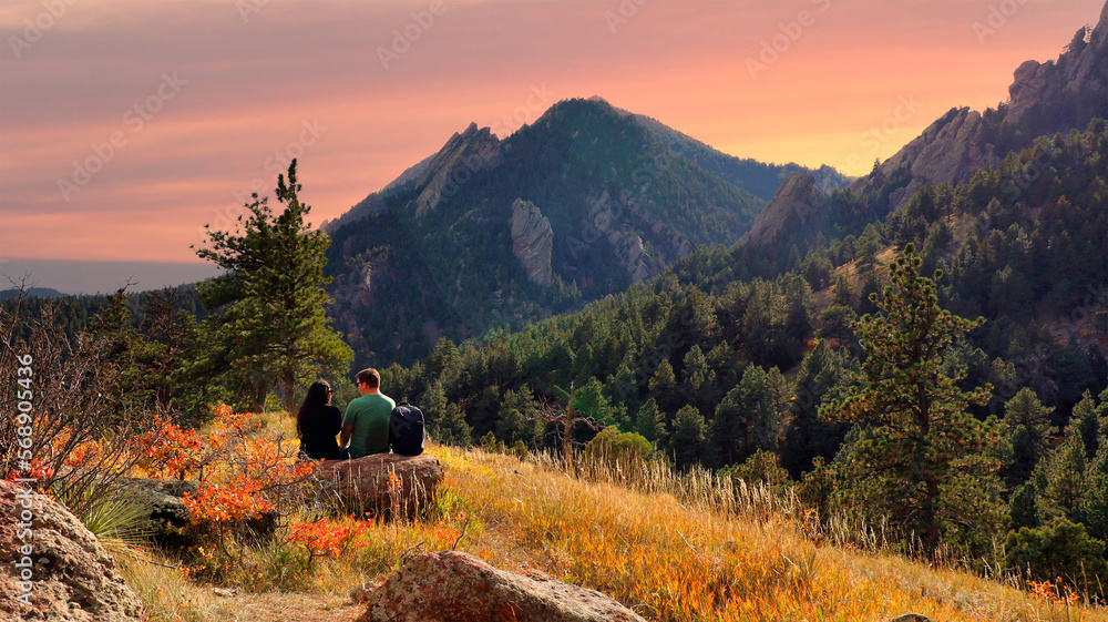 Fototapeta premium Hiking couple taking a break along Boulder, Colorado's Mesa Trail at dusk