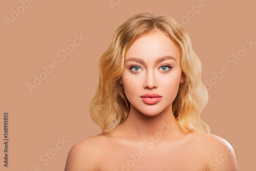 Beauty portrait of a young blonde woman with curly hair and light makeup on her face. beautiful plump lips - flesh color, the model is looking at the camera. isolated. colored background  photo