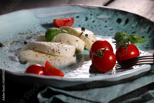 Traditional italian plate with white mozzarella, cherry tomato, basil and olive oil.