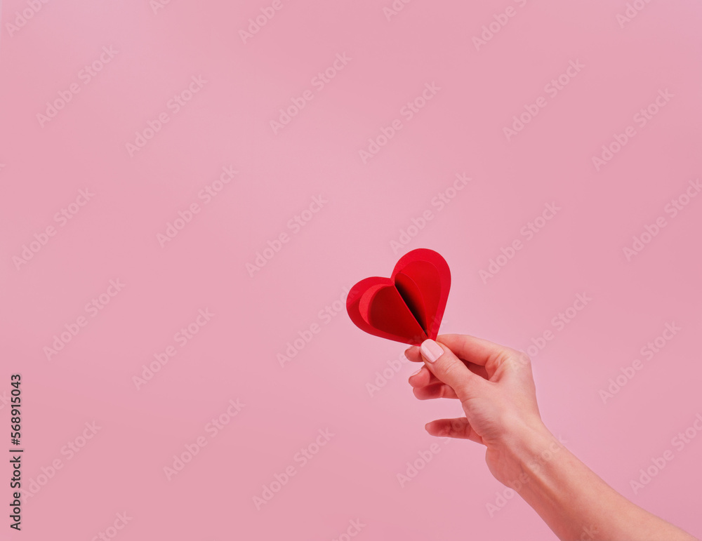Valentines day card with paper heart in hand on pink background 