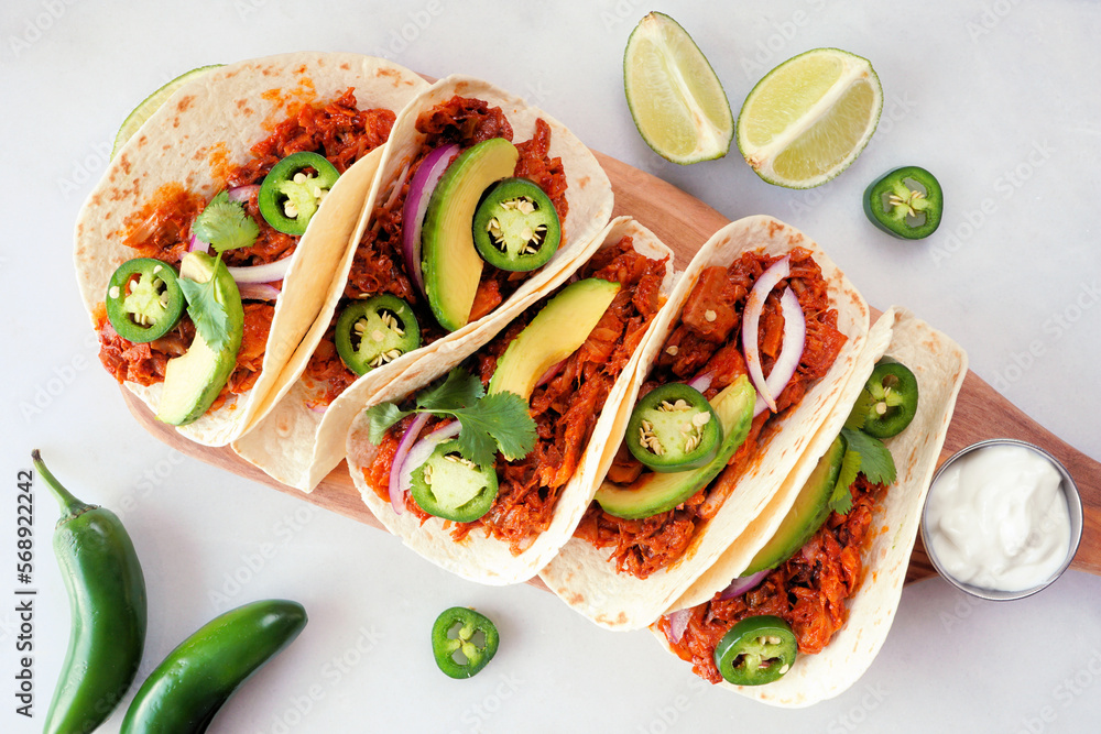 Jack fruit vegan tacos. Above table scene view on a white marble background. Healthy eating, plant-based pulled pork meat substitute. Jack fruit vegan tacos. Above table scene view on a white marble background. Healthy eating, plant-based pulled pork meat substitute.