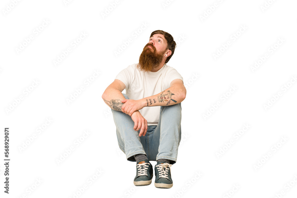 Adult redhead man sitting on the floor isolated Adult redhead man sitting on the floor isolated