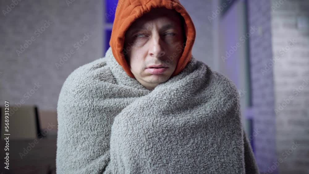 man is freezing wrapped in a blanket because of the weak heating in the apartment man is freezing wrapped in a blanket because of the weak heating in the apartment