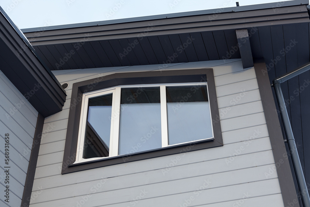 Fototapeta premium White plastic three-leaf window of a wooden cottage on the second floor