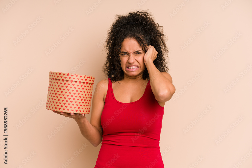 Young african american woman holding a valentines day box gift isolated covering ears with hands. Young african american woman holding a valentines day box gift isolated covering ears with hands.
