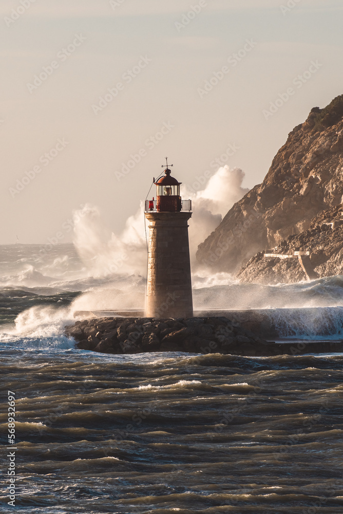 giant waves crashing on rocks and into a lighthouse, covering the building 