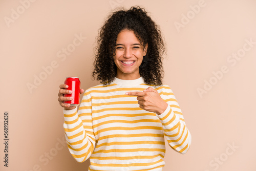 Young african american woman holding a cola refreshment isolated person pointing by hand to a shirt copy space, proud and confident