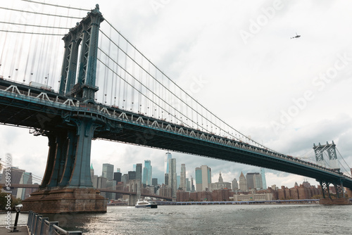 scenic view of Manhattan bridge and modern skyscrapers under cloudy sky in New York City. © LIGHTFIELD STUDIOS