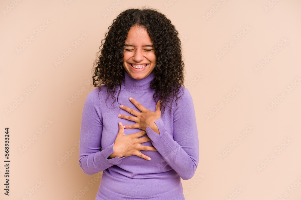 Fototapeta premium Young african american curly woman isolated laughs happily and has fun keeping hands on stomach.