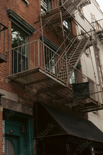 brown brick house with metal balconies and fire escape stairs in New York City.