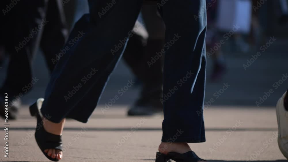 Legs of a crowd of people walking down the street, close-up of people's feet. Slow motion. Many feet walk on the pavement. Low view of crowded people walking in the square. Urban crowd. Legs of a crowd of people walking down the street, close-up of people's feet. Slow motion. Many feet walk on the pavement. Low view of crowded people walking in the square. Urban crowd.
