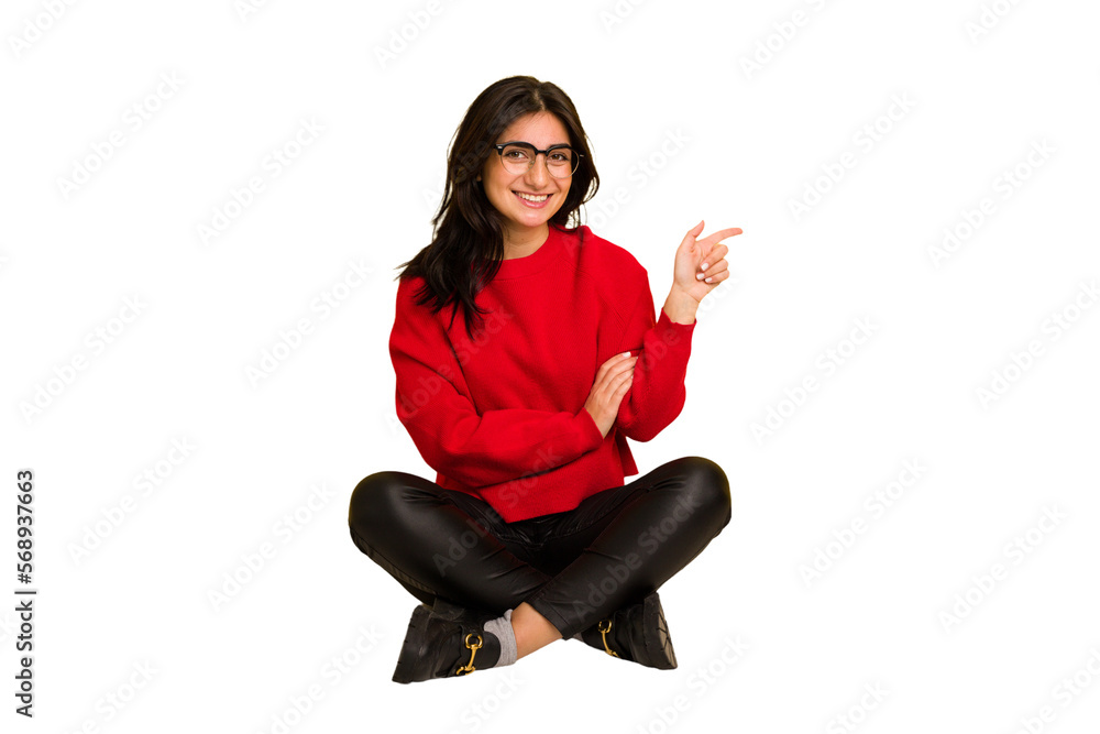Young indian woman sitting on the floor cut out isolated smiling cheerfully pointing with forefinger away. Young indian woman sitting on the floor cut out isolated smiling cheerfully pointing with forefinger away.