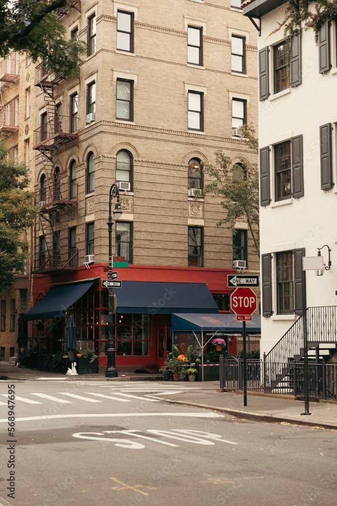building with cafe near crosswalk and road signs on urban street in New York City.