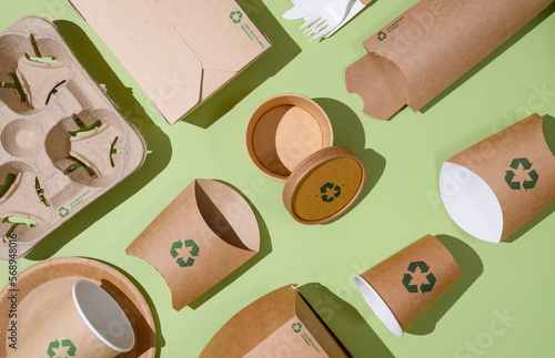 Disposable eco-friendly packaging with a recycling sign on a green background. Reusable raw materials. photo