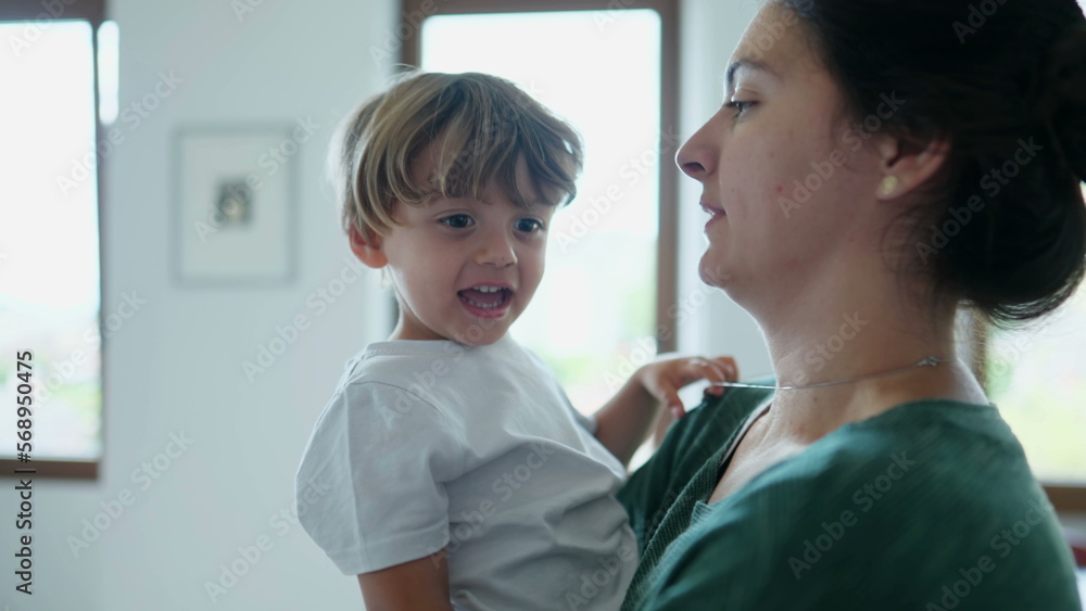 Mother holding child in arms kissing and embracing kid. Candid mom showing love affection to young boy. Authentic real life motherhood relationship Mother holding child in arms kissing and embracing kid. Candid mom showing love affection to young boy. Authentic real life motherhood relationship