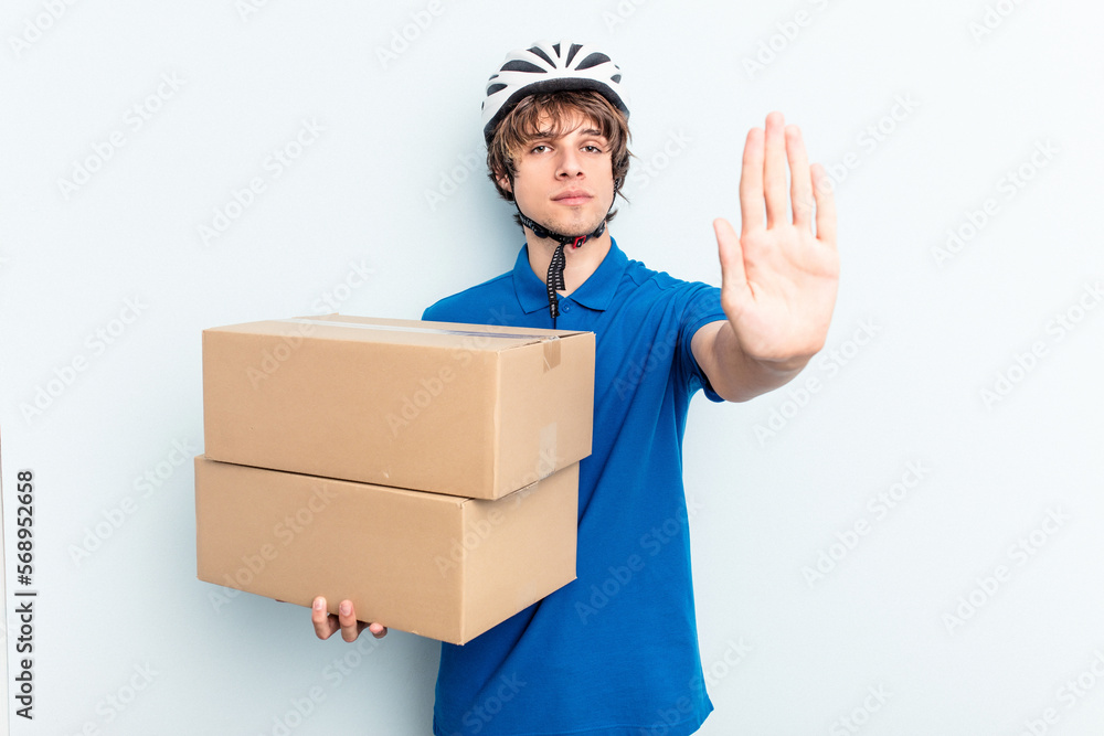 Young delivery caucasian man isolated on blue background standing with outstretched hand showing stop sign, preventing you. Young delivery caucasian man isolated on blue background standing with outstretched hand showing stop sign, preventing you.