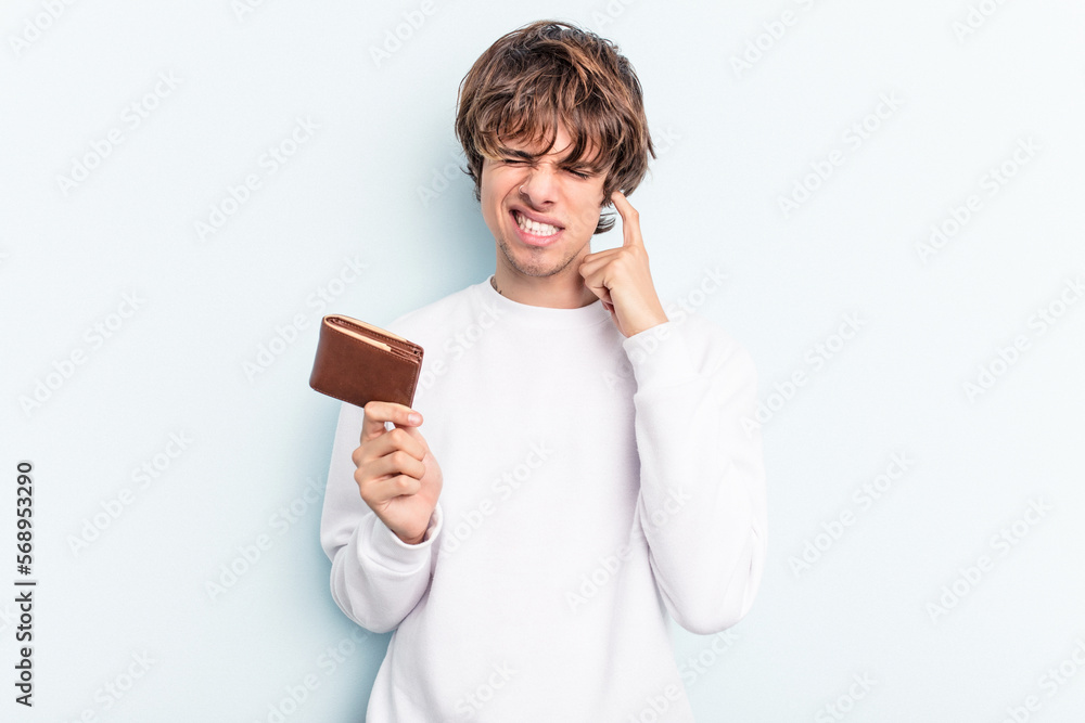 Young caucasian man holding a ballet isolated on blue background covering ears with hands. Young caucasian man holding a ballet isolated on blue background covering ears with hands.