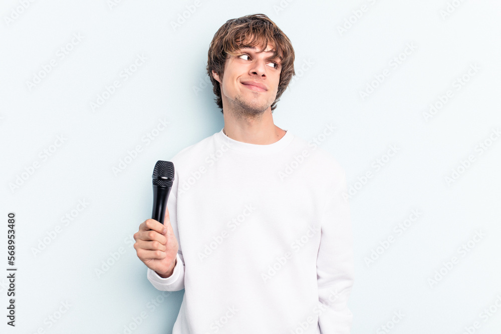 Young caucasian singer man isolated on blue background dreaming of achieving goals and purposes Young caucasian singer man isolated on blue background dreaming of achieving goals and purposes