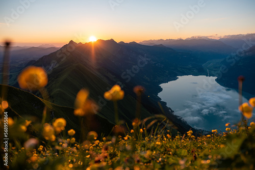 Warm sunrise with golden flower field and blue  mountain lake. photo