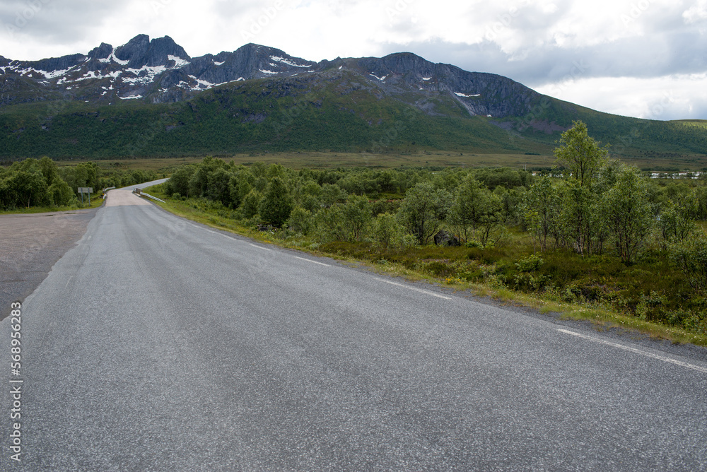 Naklejka premium Scenic road along the fjords in Norway. Amazing landscape. Northern nature. Snow-capped mountains. Dramatic clouds. Travel, adventure 