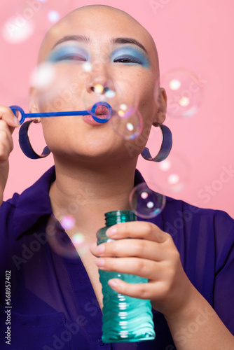 Stylish Gen Z woman blowing bubbles in colorful studio setting photo