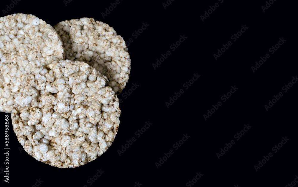 Three round rice crackers on a black background close-up. Crispy rice diet product for a healthy lifestyle. Top view puffed rice cakes on a black isolated background. Free space for text Three round rice crackers on a black background close-up. Crispy rice diet product for a healthy lifestyle. Top view puffed rice cakes on a black isolated background. Free space for text