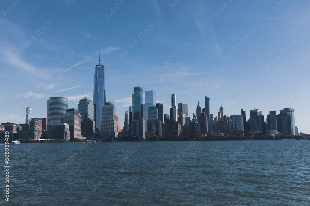 Hudson river harbor with Manhattan skyscrapers in New York City under blue sky.