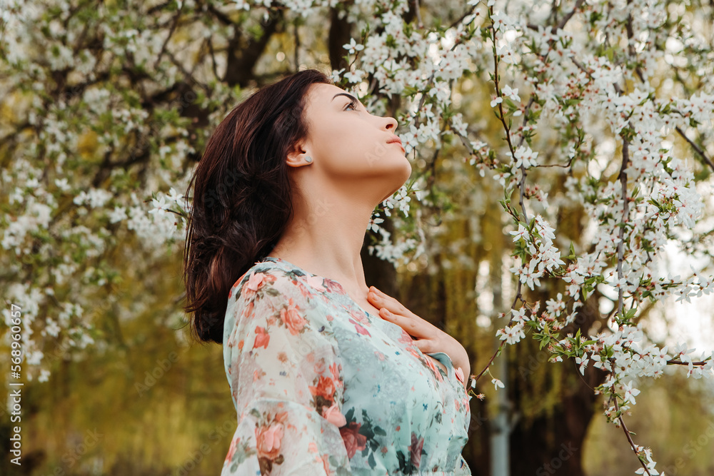 Profile pose looking to side woman dressed flowery dress posing near apple cherry tree blossoms blooming flowers in the garden park in early spring nature. Fashion, girl model with black hair
Profile pose looking to side woman dressed flowery dress posing near apple cherry tree blossoms blooming flowers in the garden park in early spring nature. Fashion, girl model with black hair