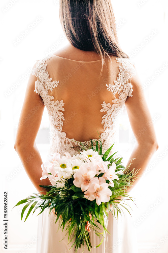 Beautiful bride in white wedding dress holding floral bouquet on her special day