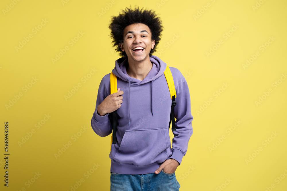 Smart smiling university student with backpack looking at camera isolated on yellow background. Education concept Smart smiling university student with backpack looking at camera isolated on yellow background. Education concept