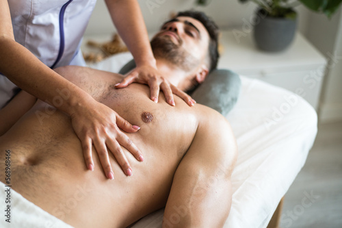 Crop masseuse massaging chest of client